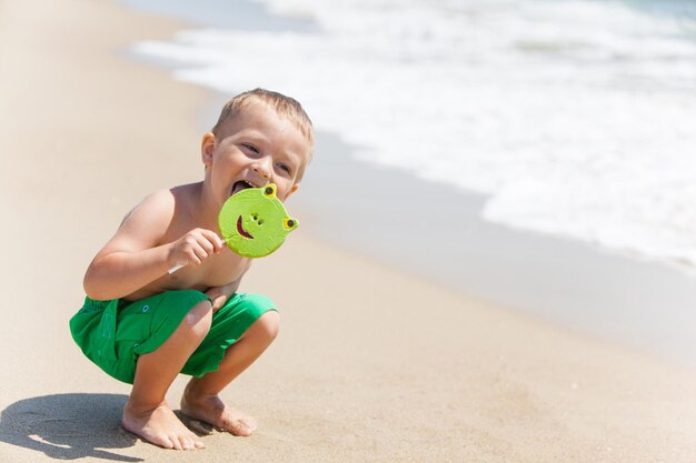 Garçon à la plage avec des bonbons souriant