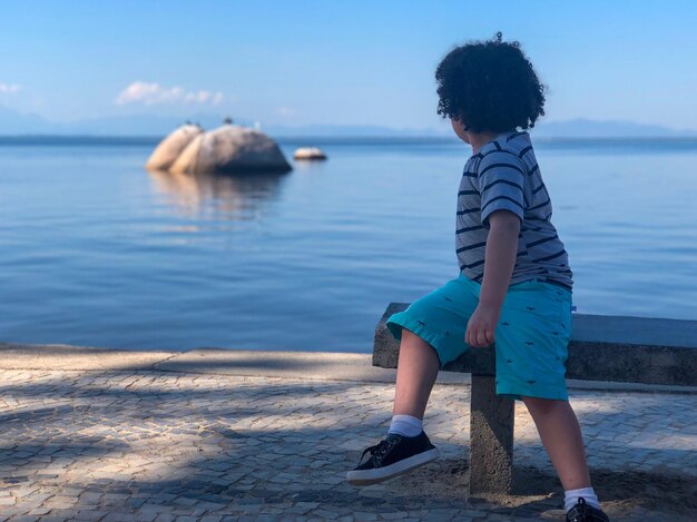 Photo un garçon sur la plage contre le ciel