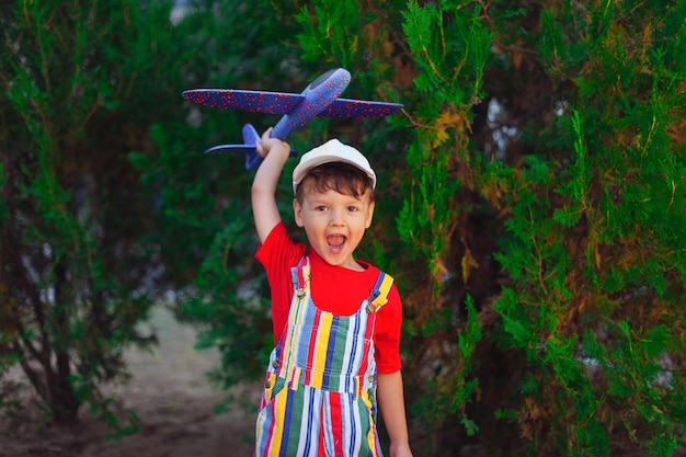 Photo garçon avec planeur dans ses mains un enfant joue avec un avion dans la rue dans le parc jouant à l'extérieur b