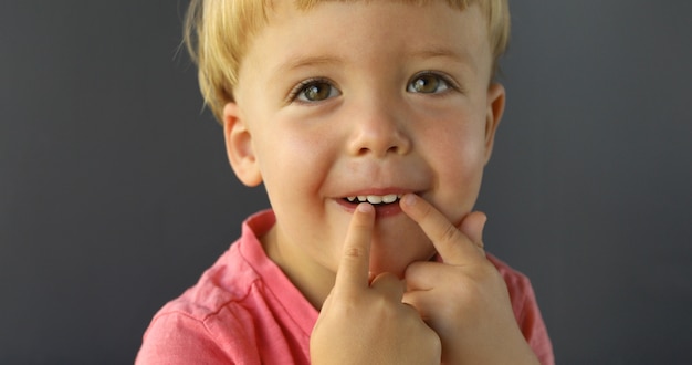 Un garçon pointe ses doigts des deux mains sur ses dents