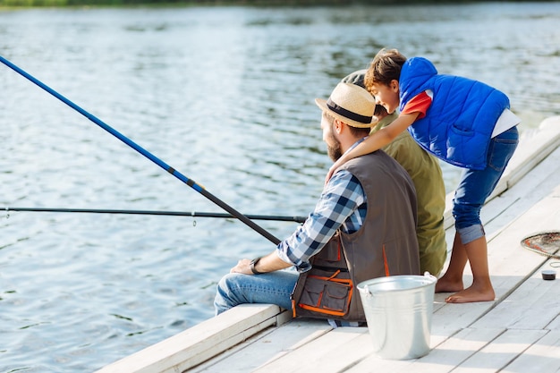 Garçon portant un gilet bleu étreignant son père et son grand-père