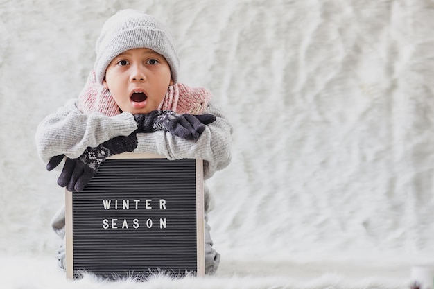 Un garçon portant des vêtements d'hiver accueille joyeusement la saison d'hiver