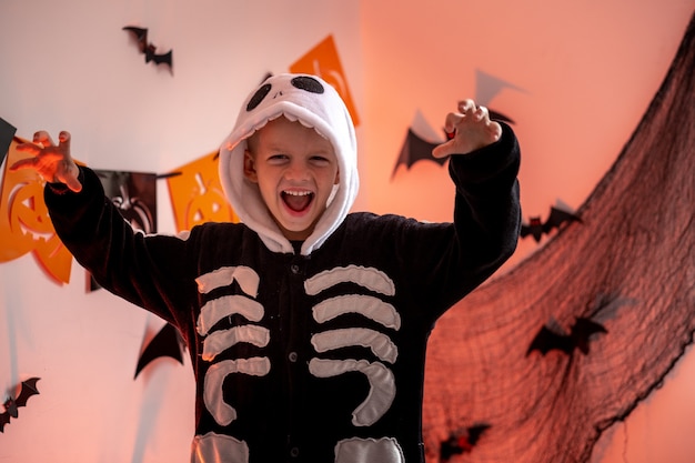 Photo garçon de portrait d'enfants d'halloween en costume de squelette d'halloween à la maison, le garçon est prêt pour le tour ou