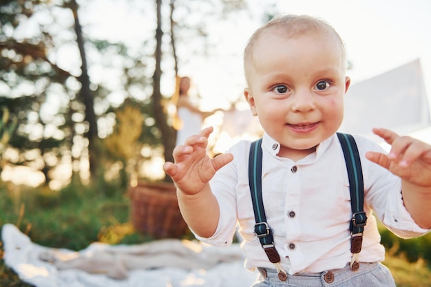 Garçon positif souriant à la caméra Jeune mère avec son petit fils est à l'extérieur dans la forêt Beau soleil