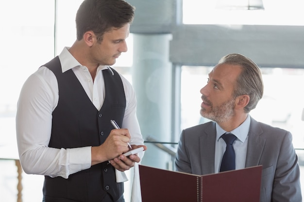 Photo garçon prenant la commande d'un homme d'affaires