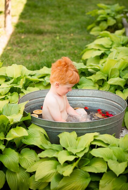 Un garçon prend un bain dans un bain d'été