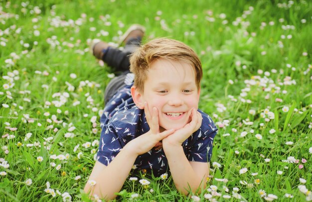 Garçon de printemps sur l'herbe enfant mignon sur le champ fleur enfant rêvant