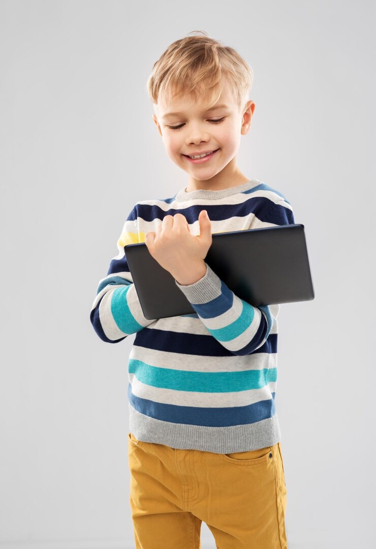 Photo un garçon en pull à rayures avec une tablette et un ordinateur