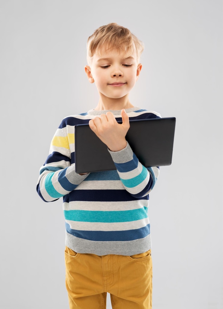 Photo un garçon en pull à rayures avec une tablette et un ordinateur