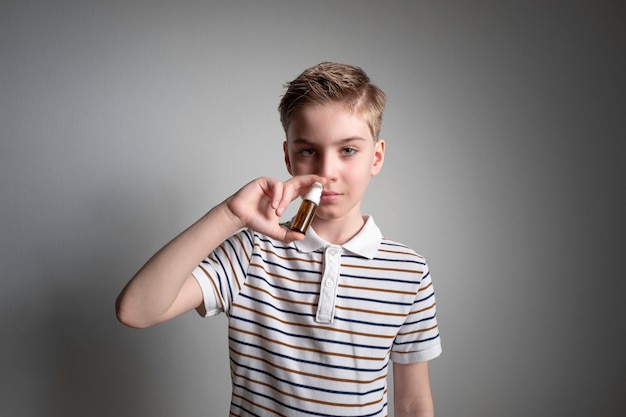 Photo le garçon pulvérise un spray nasal dans son nez pour la congestion