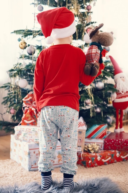 garçon en pyjama de Noël garçon sur le fond d'un arbre de Noël