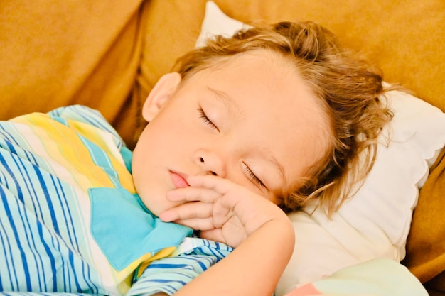 Un garçon qui dort sur le lit à la maison.