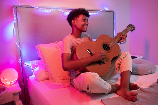 Photo un garçon qui joue de la guitare à la maison.