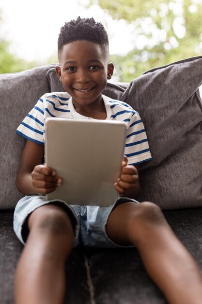 Photo un garçon qui utilise une tablette numérique dans le salon de sa maison