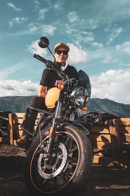 garçon de race blanche avec des lunettes de soleil sur moto jaune avec ciel coucher de soleil en arrière-plan