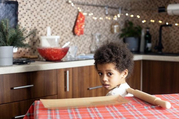 Garçon de race mixte à la peau foncée dans la cuisine décorée pour l'enfant de Noël à la maison