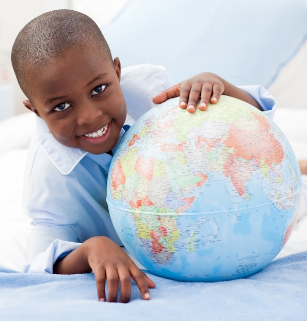 Garçon regardant un globe en souriant à la caméra