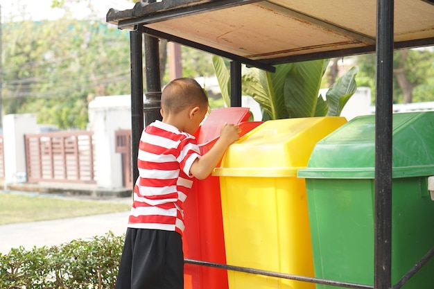 Garçon regardant des poubelles dans le jardin