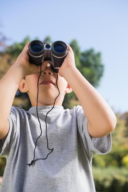 Garçon regardant à travers les jumelles vers le ciel