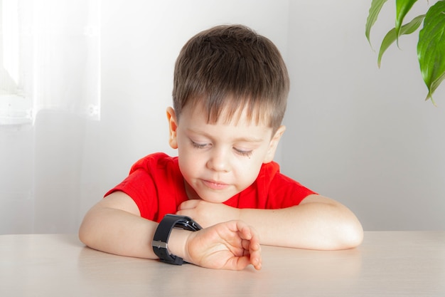 Le garçon regarde l'heure sur l'horloge