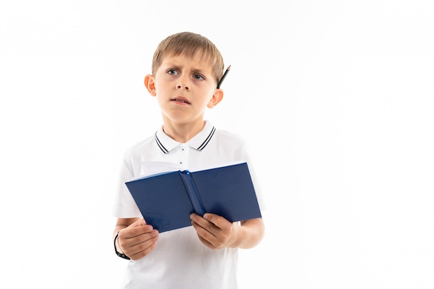 garçon regarde avec un livre et un stylo dans ses mains sur blanc