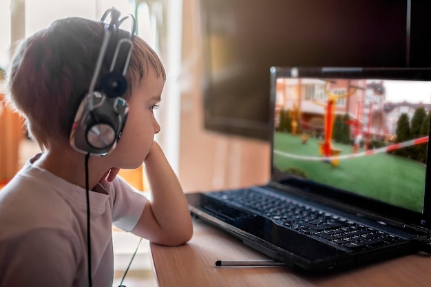 Photo un garçon regarde des nouvelles chaudes sur un terrain de sport et une aire de jeux fermés via internet sur l'écran de son ordinateur portable