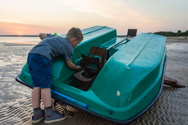 Un garçon répare un bateau sur le rivage d'une baie de mer un vieux catamaran une hélice un garçon mécanicien