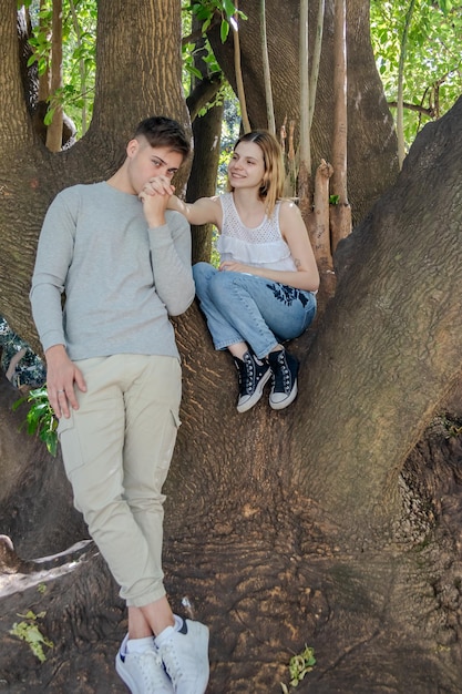 Photo un garçon romantique embrassant la main de sa petite amie sur un arbre dans le parc