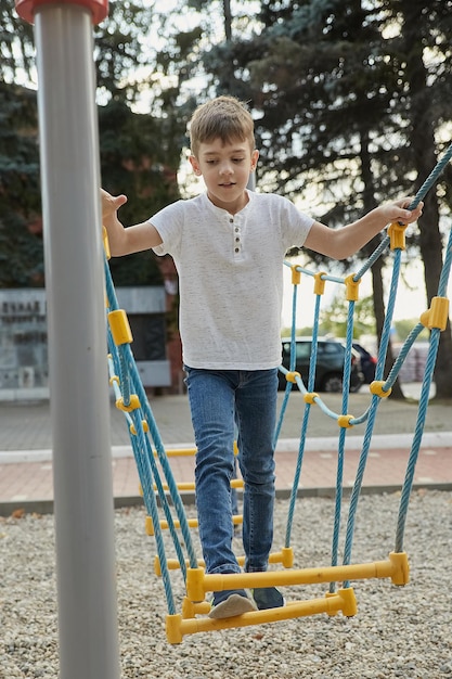 Garçon s'amusant à l'extérieur petit enfant caucasien maigre jouant au terrain de jeu