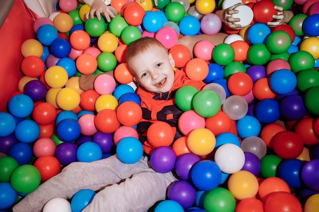 Le garçon s'amuse dans la piscine avec des boules colorées. enfance heureuse.