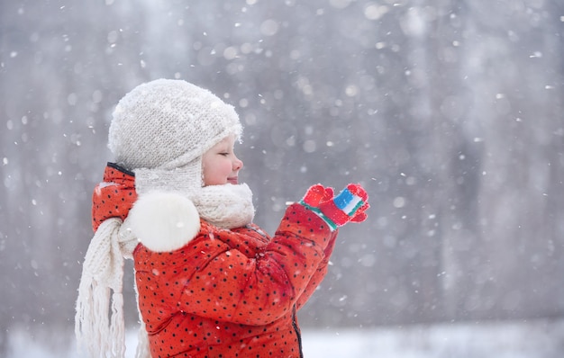 Un garçon et sa sœur cadette marchent dans le parc un jour d'hiver enneigé