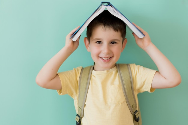 Le garçon avec le sac à dos d'école tient le livre