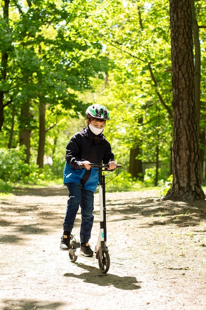 Garçon sur un scooter dans un casque et un masque médical