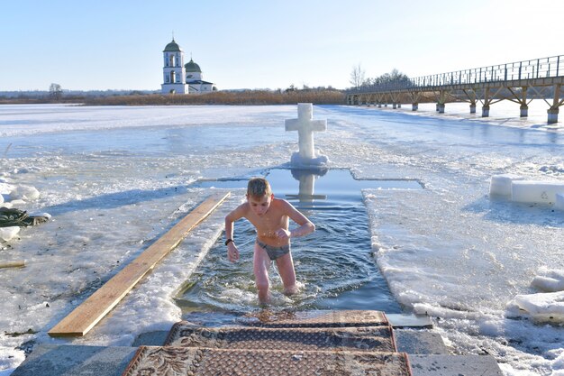 Photo le garçon se baigne dans l'eau froide. baptême. baignade dans un trou.