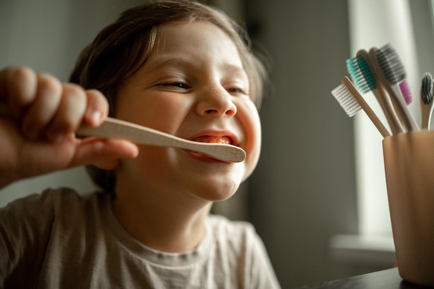 Le garçon se brosse les dents avec une brosse à dents en matériau écologique