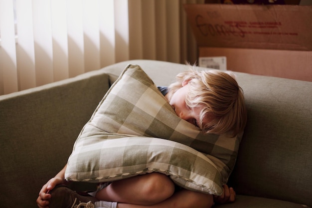 Un garçon se détend avec un coussin sur le canapé à la maison.