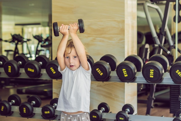 Un garçon se lève, un haltère dans la salle de gym