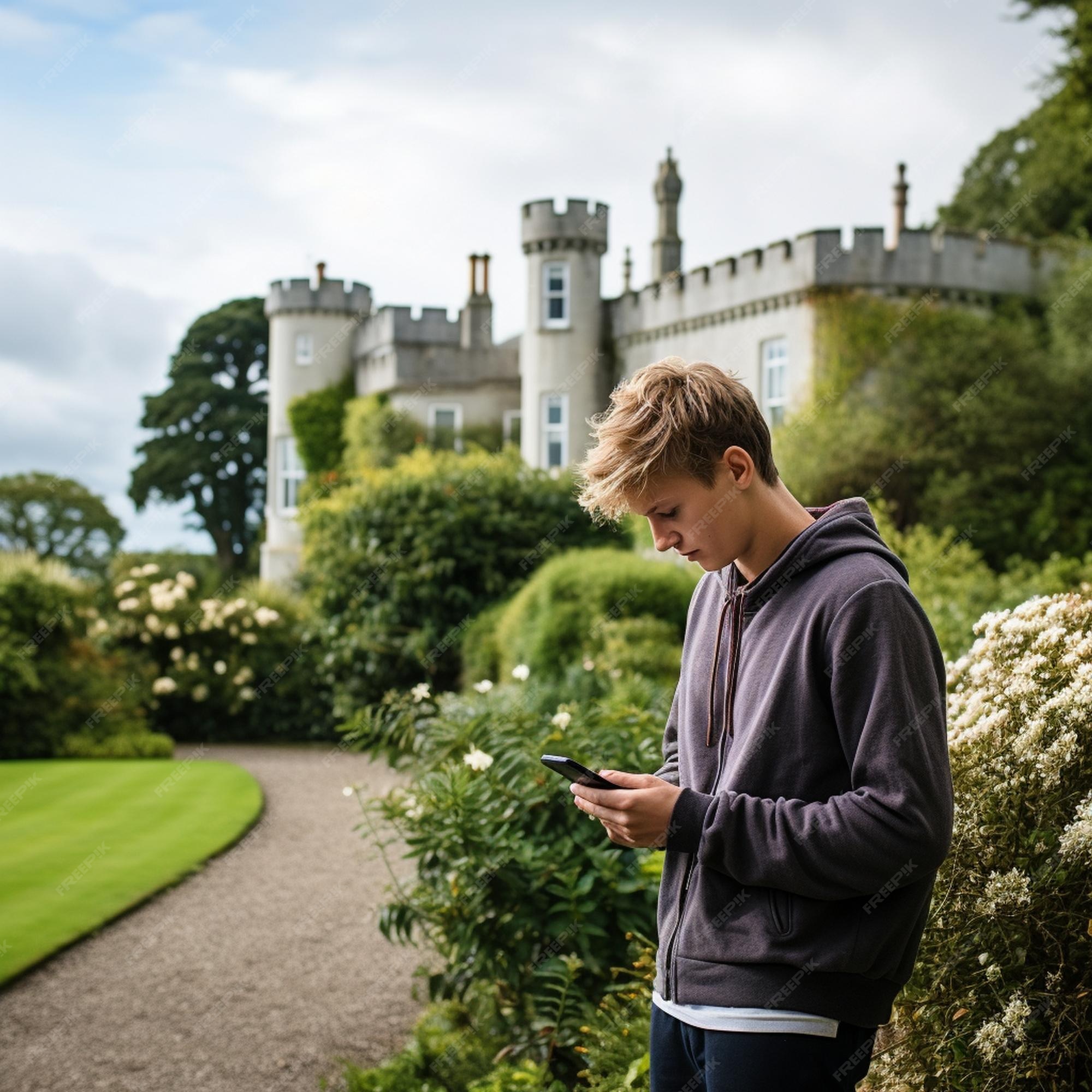 Un Garçon Se Tient Devant Un Château Avec Un Téléphone Portable