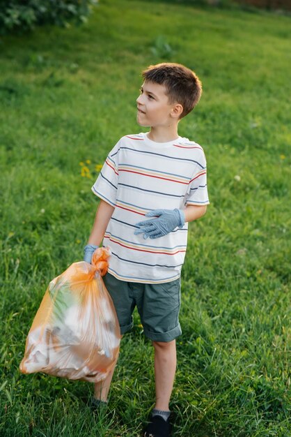 Un garçon de sept ans au coucher du soleil est engagé dans la collecte des ordures dans le parc Recyclage des soins environnementaux