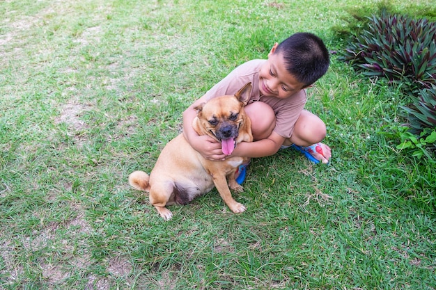 Le garçon serre son chien dans les bras.