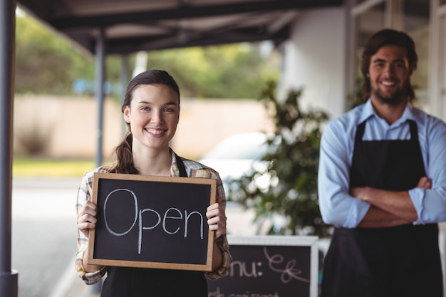 Garçon et serveuse debout avec tableau noir avec panneau ouvert