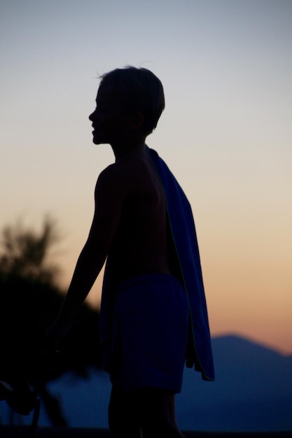 Photo un garçon en silhouette debout contre le ciel au coucher du soleil