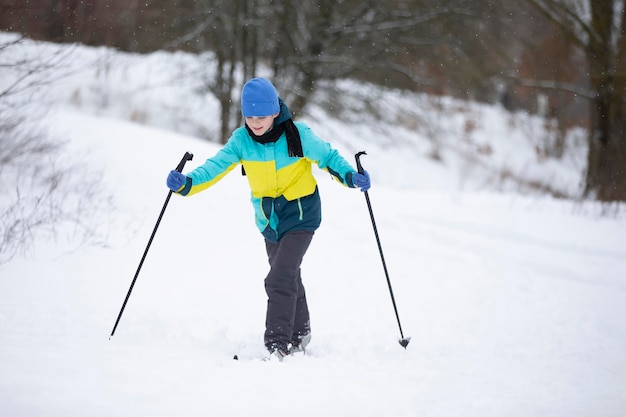 Le garçon skie dans la forêt d'hiver