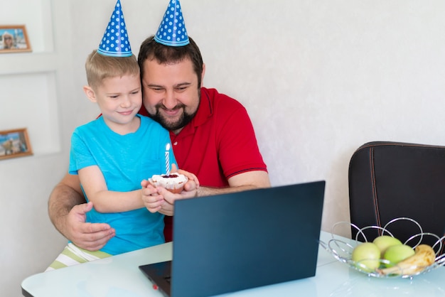 Un garçon et son père célèbrent un anniversaire en ligne