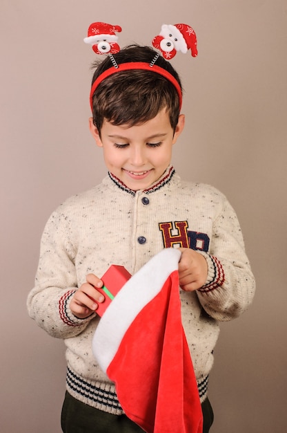 Photo le garçon sort un cadeau du chapeau du père noël