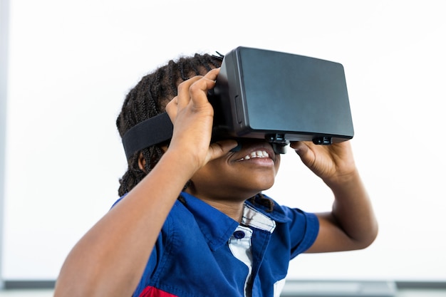 Garçon souriant à l'aide d'un casque de réalité virtuelle en classe
