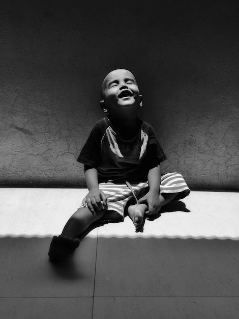 Un garçon souriant assis sur le sol à la maison