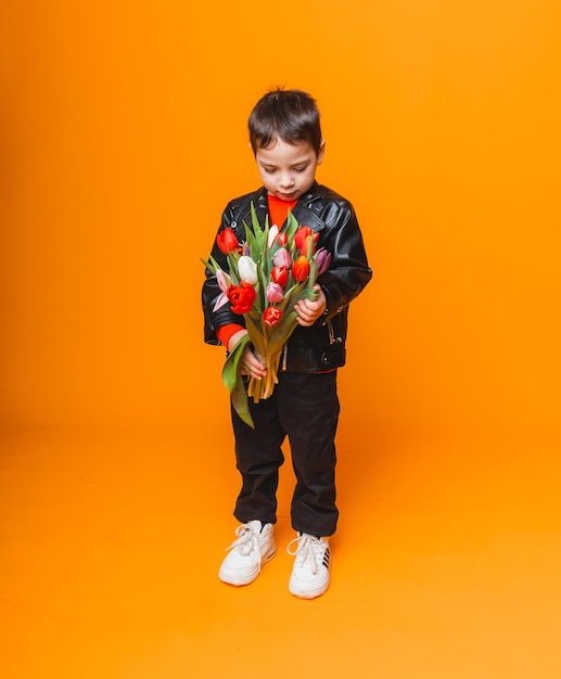 Garçon souriant avec bouquet de fleurs de printemps de tulipes isolé sur jaune