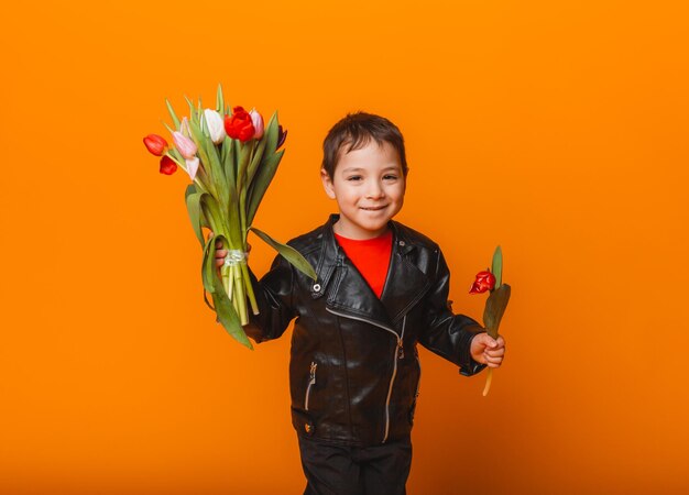 Garçon souriant avec bouquet de fleurs de printemps de tulipes isolé sur jaune