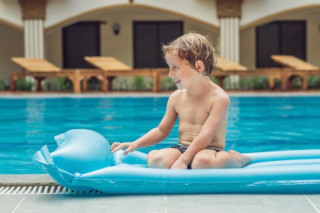 Garçon souriant sur matelas gonflable bleu dans la piscine